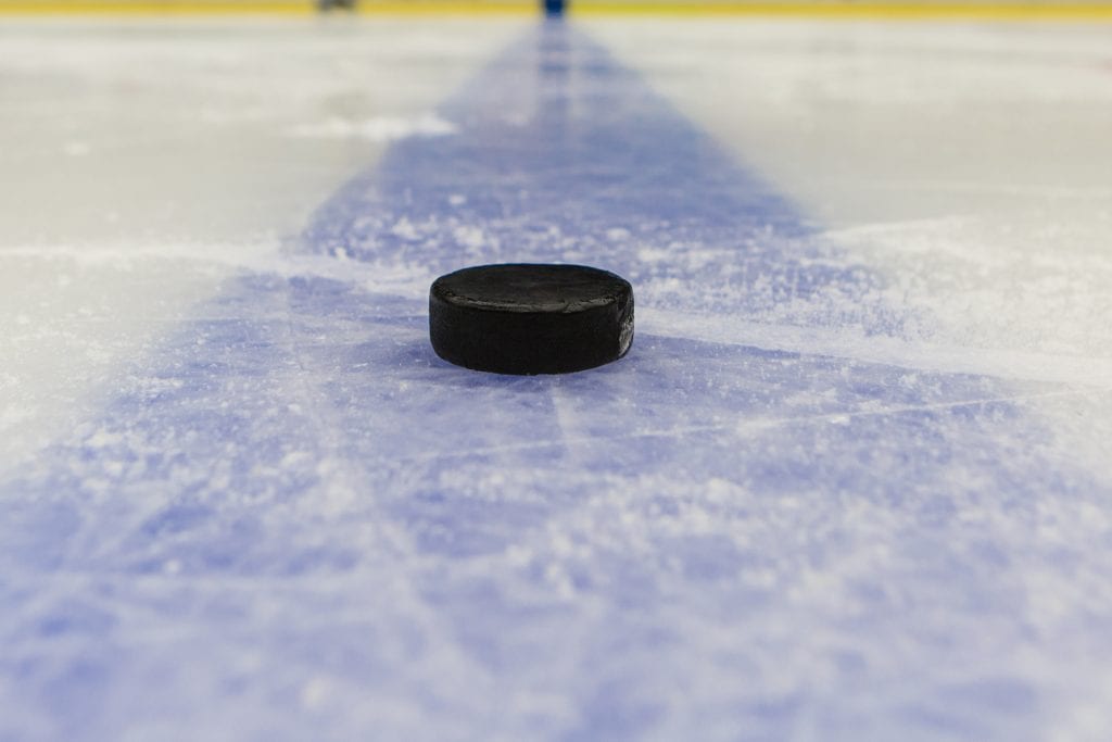 detail blue line with puck on ice hockey rink